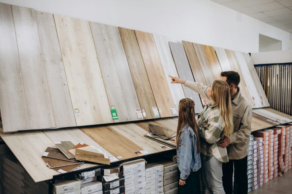 Modern family couple standing together with sample of laminated flooring in building store